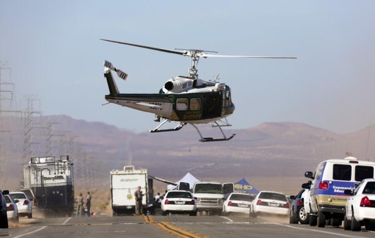 Law enforcement helicopters and police cruisers block Highway 395 between Kramer Junction and Ridgecrest after a suspect who opened fire on passersby during an hourlong police pursuit in Central California was killed and two people found with bullet wounds in the trunk of his vehicle were airlifted to an area hospital.