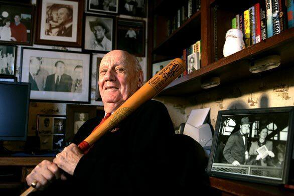 Emil J. "Buzzie" Bavasi, former general manager of the Dodgers, holds his 1955 Brooklyn Dodgers World Series bat at his La Jolla. Caif., home. On the desk is a photo of Bavasi and his wife, Evit, at Ebbets Field during the 1955 series. Bavasi, who shepherded the Dodgers through their World Series-studded transition from Brooklyn to Los Angeles, has died. He was 92.