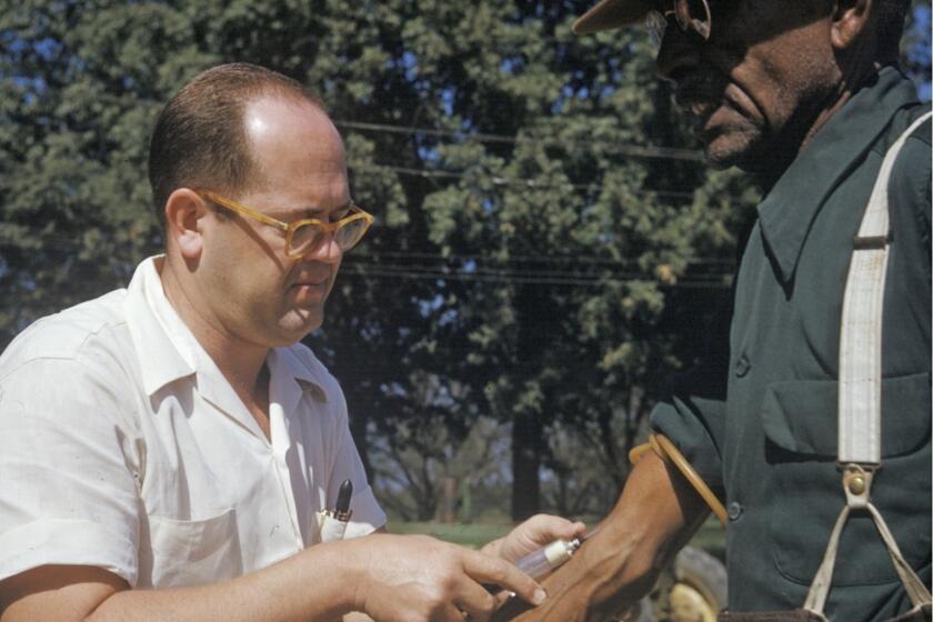 In this 1950's file photo released by the National Archives, a black man included in a syphilis study has blood drawn by a doctor in Tuskegee, Ala. Most Black Americans are likeliest to say that they experience racial discrimination regularly and that such experiences inform how they view major U.S. institutions, according to a new study from the Pew Research Center released Monday, June 10, 2024. The study seeks to highlight the country's documented racist history against Black people as a possible explanation for why Black Americans hold conspiratorial views about major U.S. institutions. (National Archives via AP)