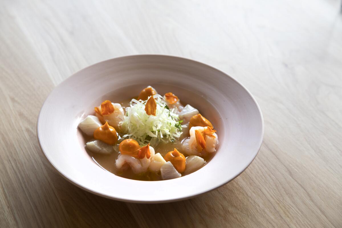 A photo of a bowl of Causita's ceviche ceviche mixto on a wooden tabletop.