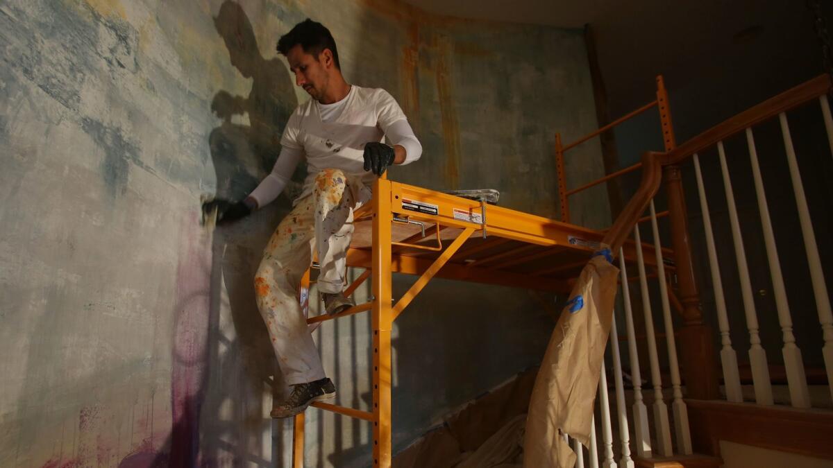 Ceballos works on a mural along the staircase of the Filasky home in La Costa.