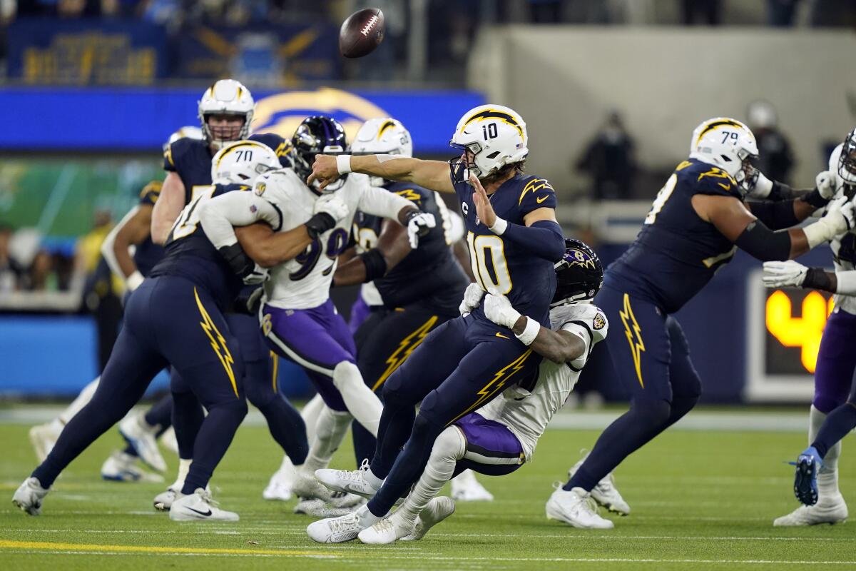 Chargers quarterback Justin Herbert (10) is tackled by Ravens cornerback Arthur Maulet on a fourth-down blitz.