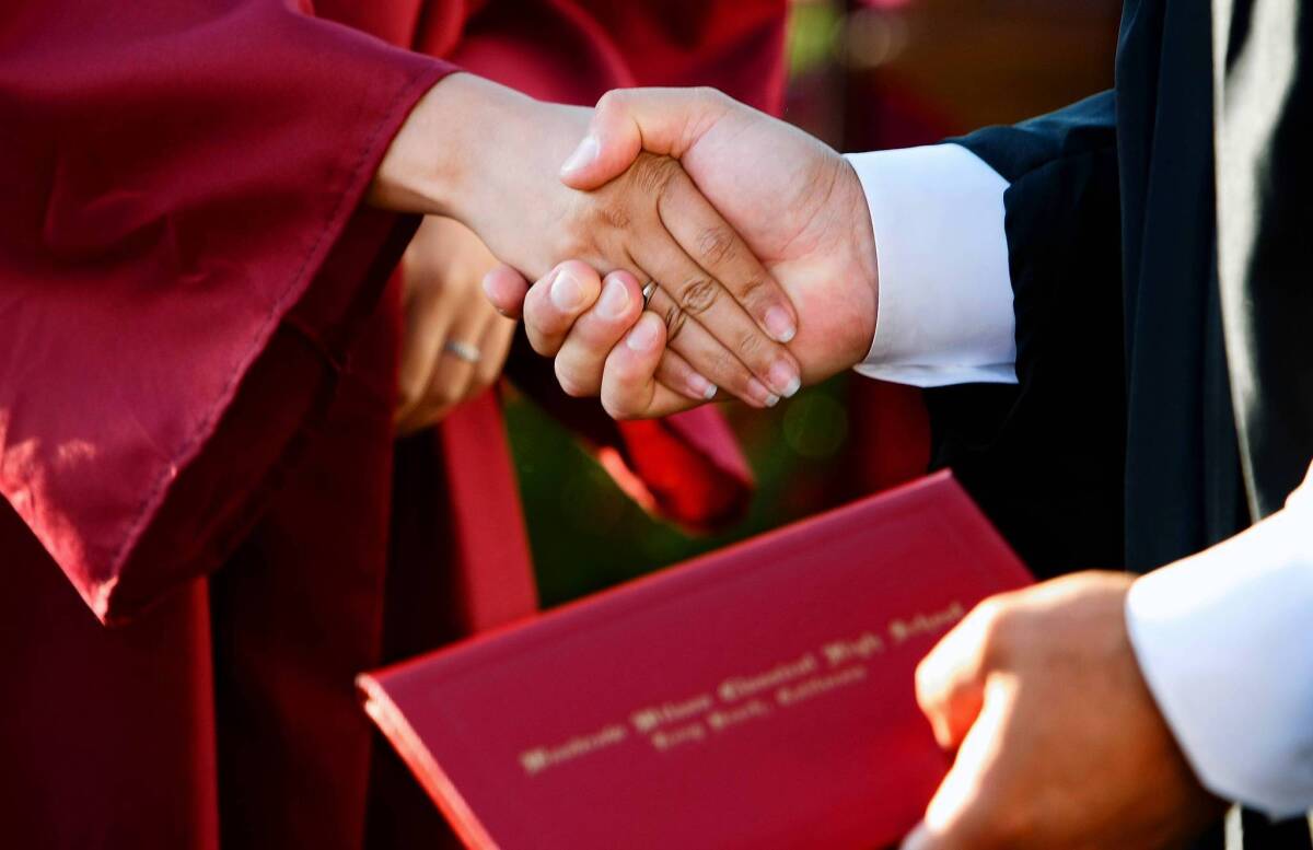 Gonzalo Moraga, right, principal of instruction at Woodrow Wilson Classical High School in Long Beach, shakes hands with a graduate during the school's commencement ceremony. Moraga said that he shook hands with over 400 students during the ceremony.