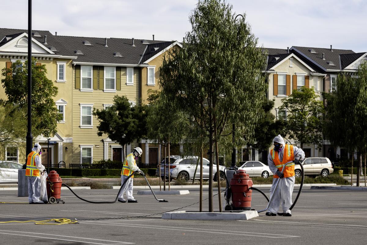 A cleanup crew vacuums debris spewed into neighborhoods by the Tustin hangar fire.