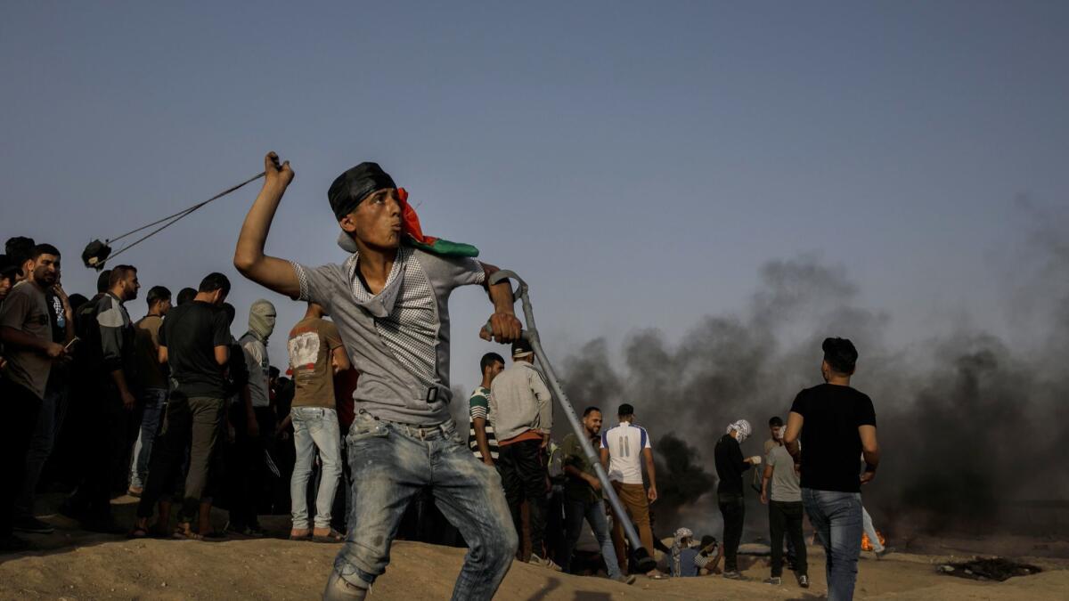A Palestinian protester flings rocks toward the Gaza Strip's border with Israel and Gaza on Friday.