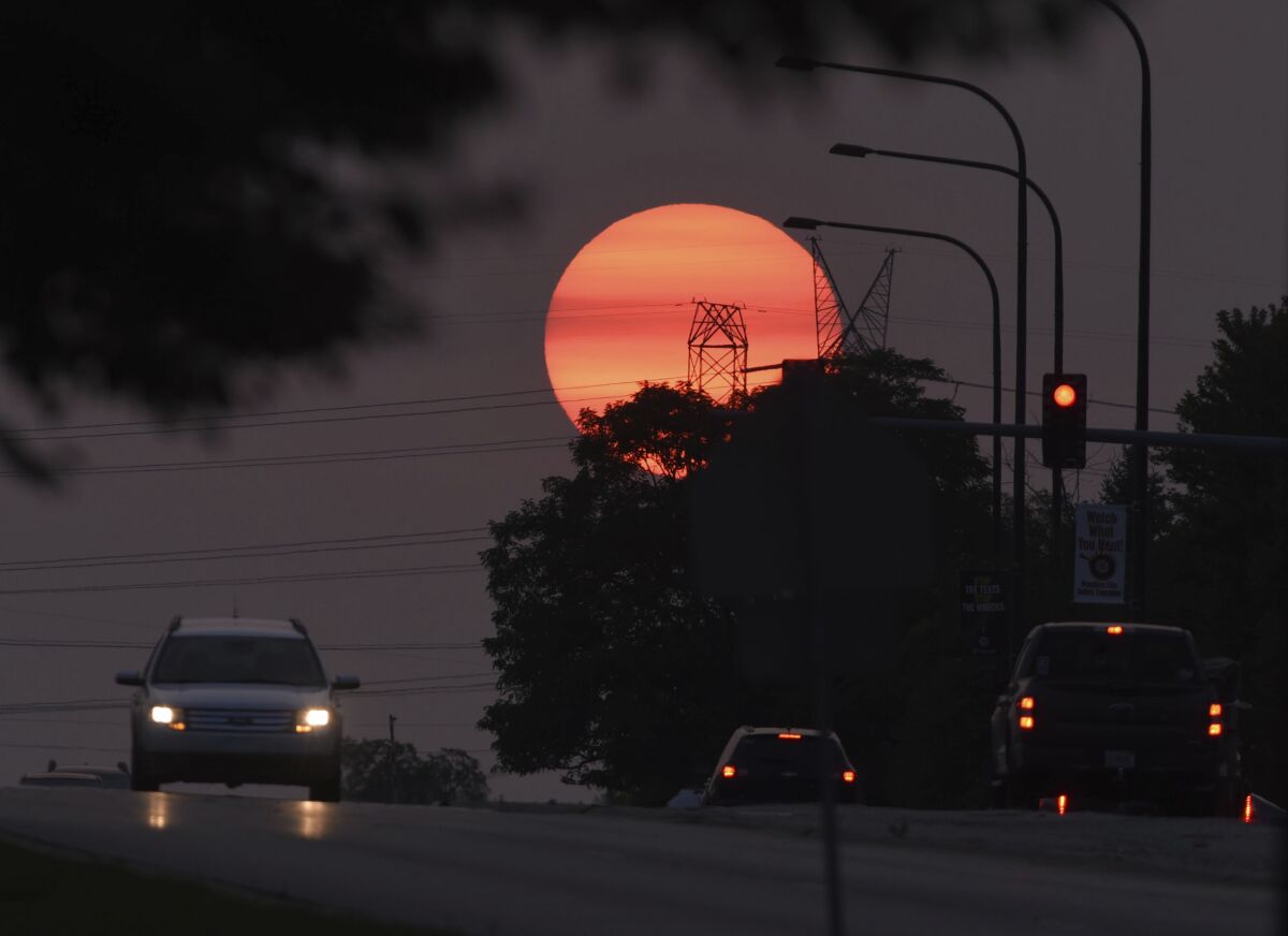 Traffic flows on Townline Road as a hazy sun sets in Vernon Hills, Ill,, Tuesday, Sept. 15, 2020. The smoke from dozens of wildfires in the western United States has now blanket much of the county along with parts of Mexico and Canada, as residents thousands of miles away on the East Coast are being treated to unusually hazy skies and remarkable sunsets. (John Starks/Daily Herald via AP)