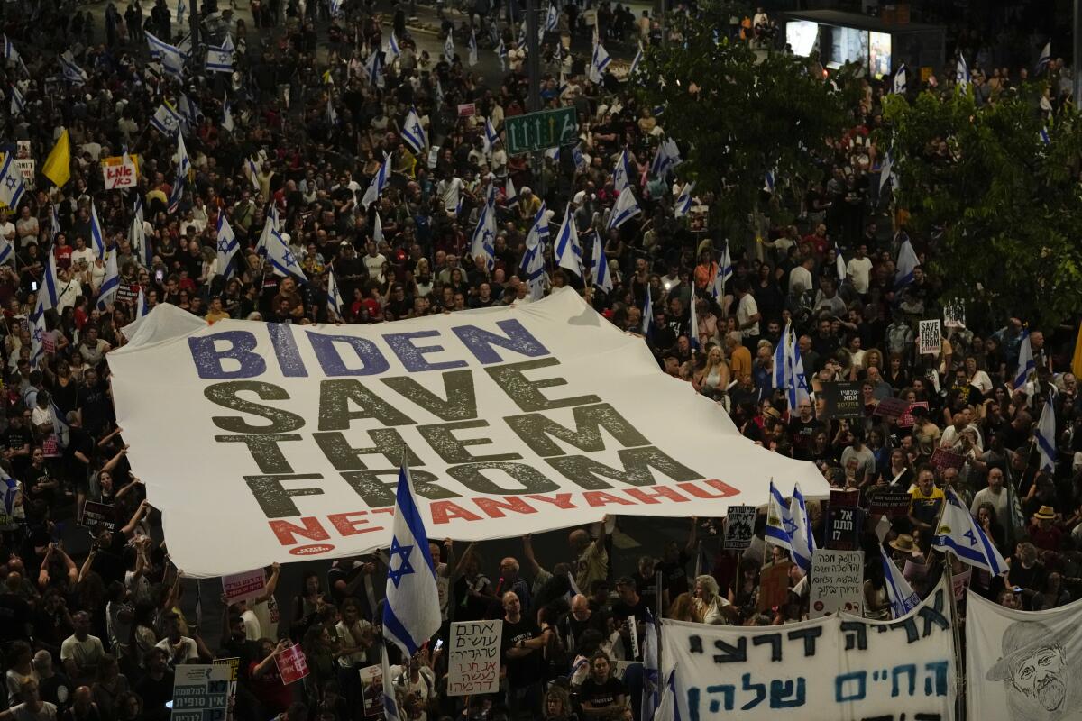 People in a crowd hold a massive banner overhead that reads "Biden save them from Netanyahu."
