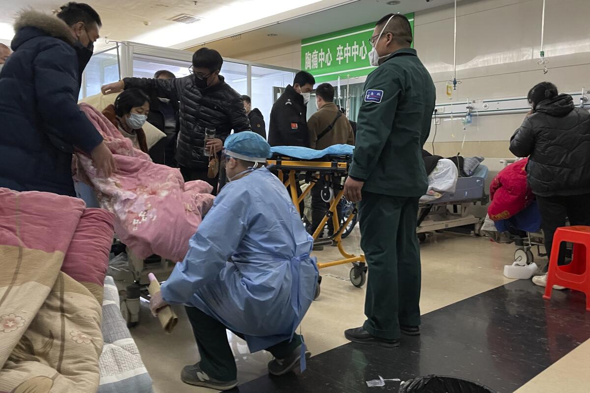 A patient is moved onto a gurney in an emergency room crowded with sick people