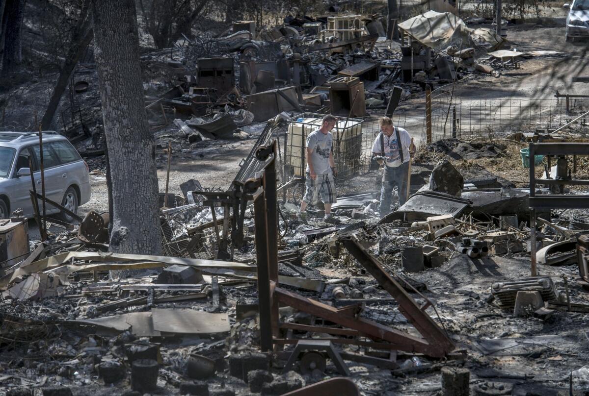 On Sept. 24, Daniel Hawkins, left, and his father, Steve Dowing, search through the remains of their Mountain Ranch, Calif., property, which was destroyed in the Butte fire.