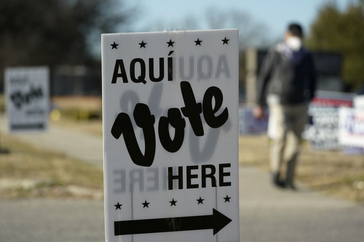 FILE - A man passes an early voting poll site, on Feb. 14, 2022, in San Antonio. Voters in heavily Hispanic parts of South Texas cast record numbers of ballots in the state's Republican primary last week, leaving the GOP excited about a growing shift toward their party. (AP Photo/Eric Gay, File)