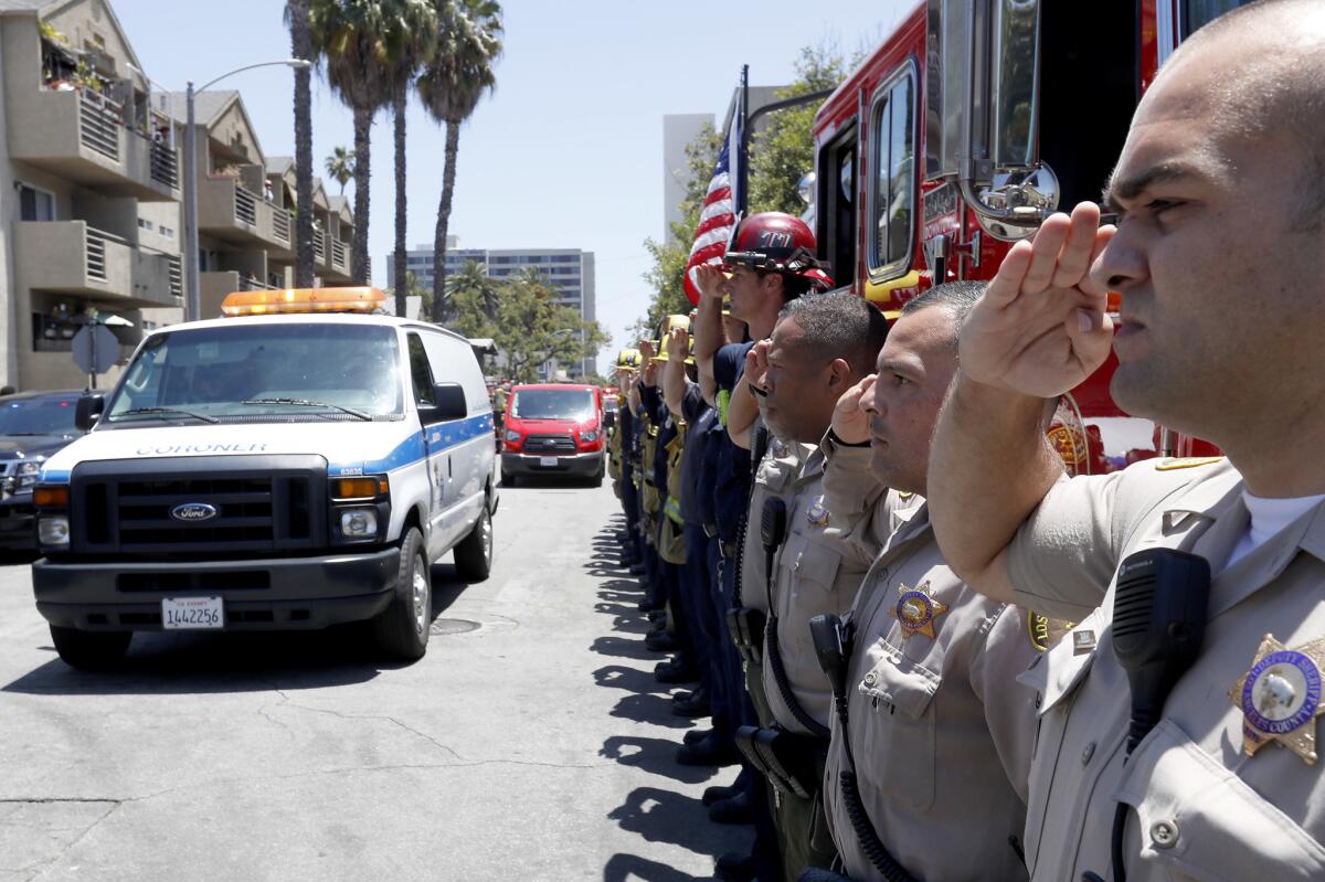 Police and fire personnel salute as a coroner's van bearing the body of Long Beach Fire Department Capt. Dave Rosa, 45, passes down 11th Street in Long Beach.
