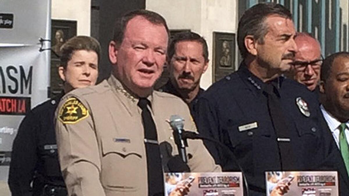 Los Angeles County Sheriff Jim McDonnell and LAPD Chief Charlie Beck announce a new phone app for reporting suspected terrorist activity at a news conference at the Los Angeles Memorial Coliseum.