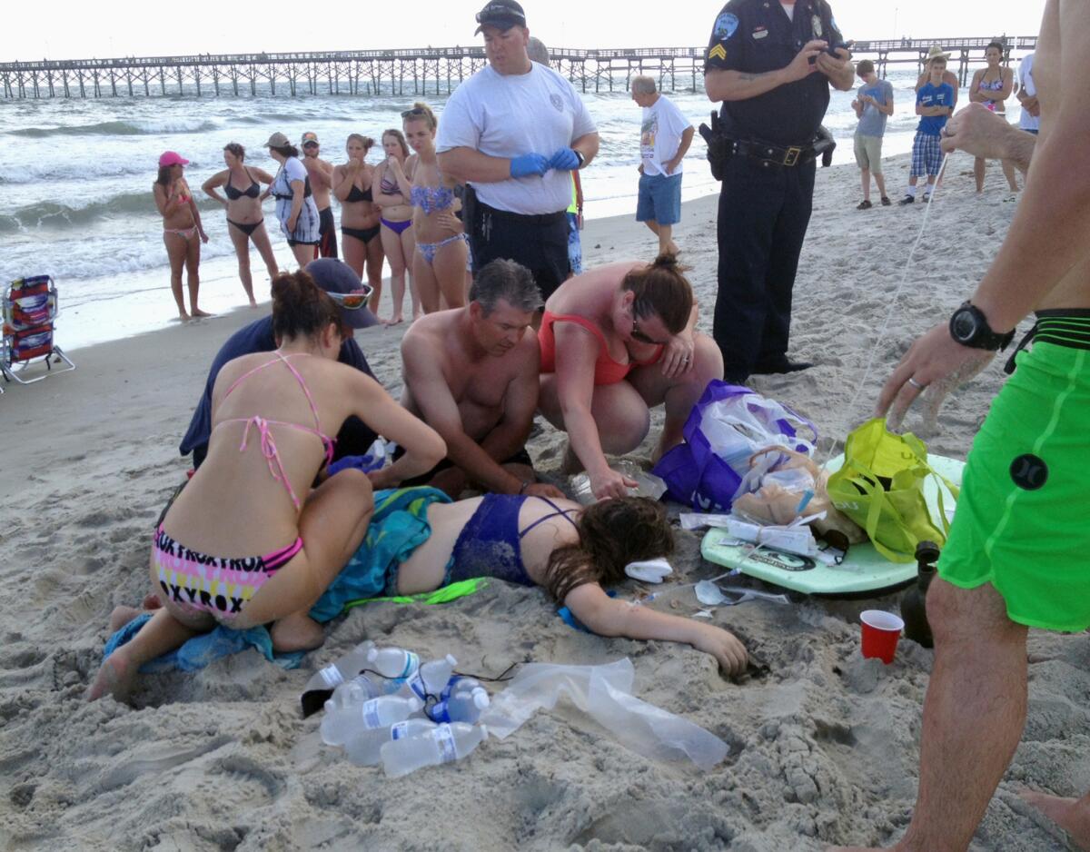 Varias prestan prestan primeros auxilios a una joven en el lugar de un ataque de tiburón en Oak Island, Carolina del Norte, el domingo 14 d ejunio de 2015.