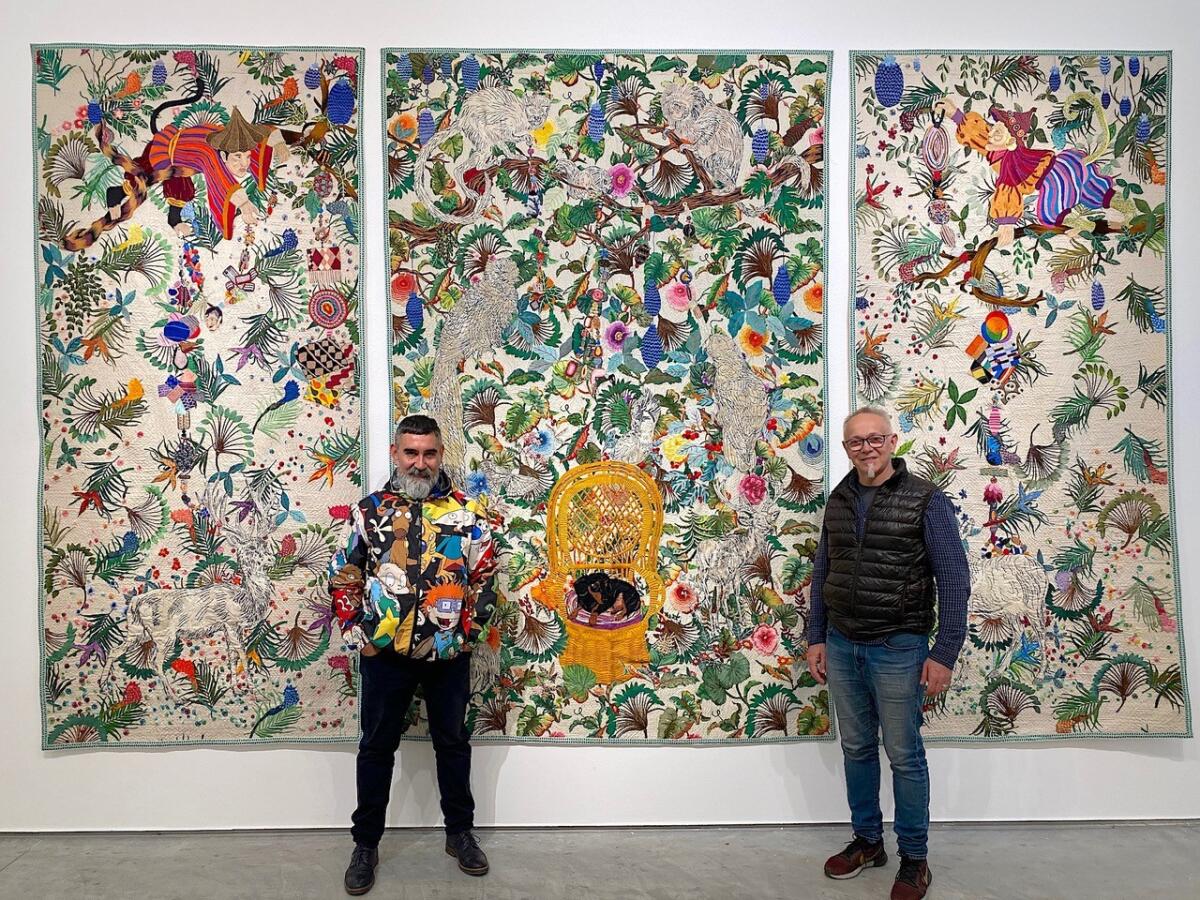 Leo Chiachio and Daniel Giannone pose with “Selva Blanca,” (White Forest), a triptych that took them three years to complete. In the upper corners are portraits of the artists as costumed monkeys. In the golden chair is their #1 dog, Piolin, now 15 years old.