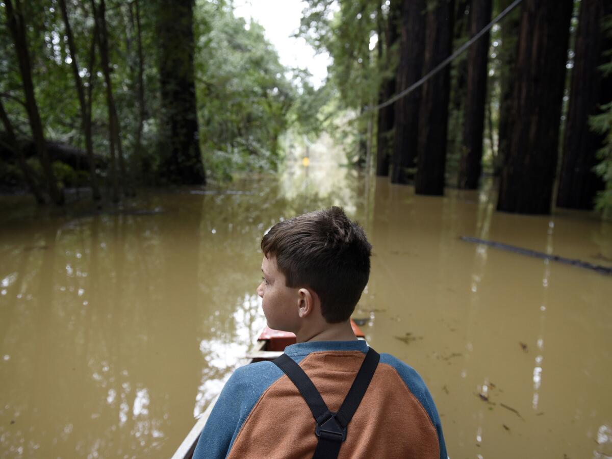 Mathais McCarthy looks around while canoeing down a street flooded by the waters of the Russian River in Forestville.