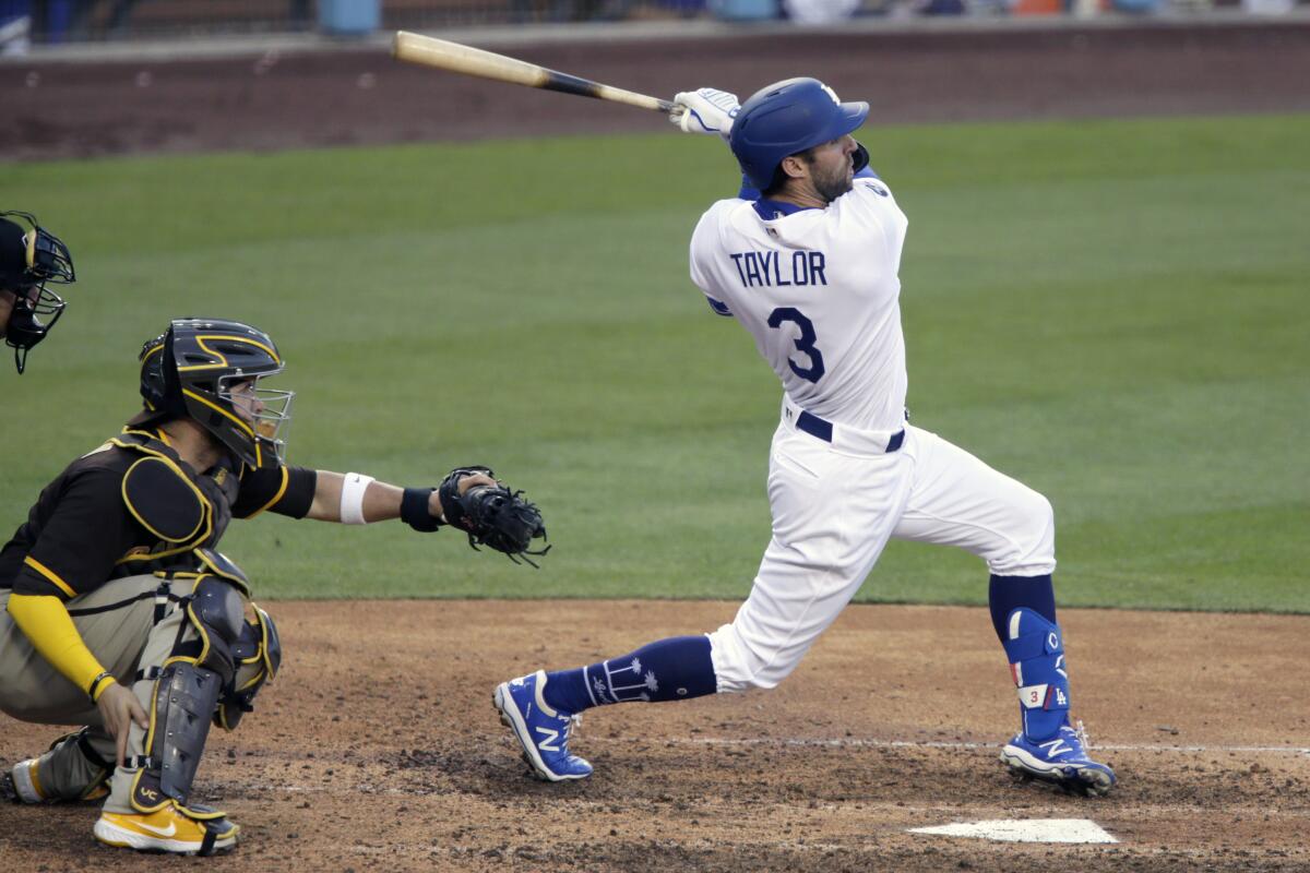Dodgers second baseman Chris Taylor follows through to hit a three-run home run in front of Padres catcher Victor Caratini.