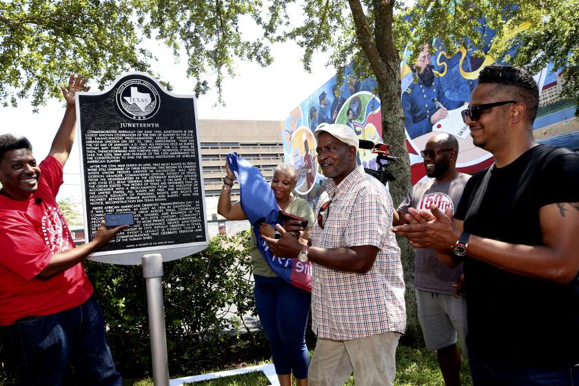 Sam Collins III, left, and others celebrate at the Juneteenth historical marker in Galveston after President Joe Biden signed the Juneteenth National Independence Day Act into law on Thursday, June 17, 2021. (Jennifer Reynolds/The Galveston County Daily News via AP)