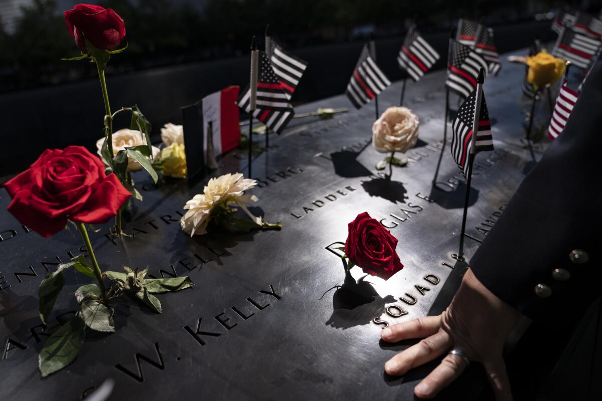 A firefighter places his hand on the name engravings on the south pool during ceremonies to commemorate the 20th anniversary of the Sept. 11 terrorist attacks, Saturday, Sept. 11, 2021, at the National September 11 Memorial & Museum in New York. (AP Photo/John Minchillo)
