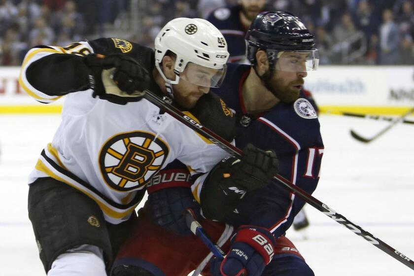 Boston Bruins' Matt Grzelcyk, left, and Columbus Blue Jackets' Brandon Dubinsky chase a loose puck during the second period of Game 3 of an NHL hockey second-round playoff series Tuesday, April 30, 2019, in Columbus, Ohio. (AP Photo/Jay LaPrete)