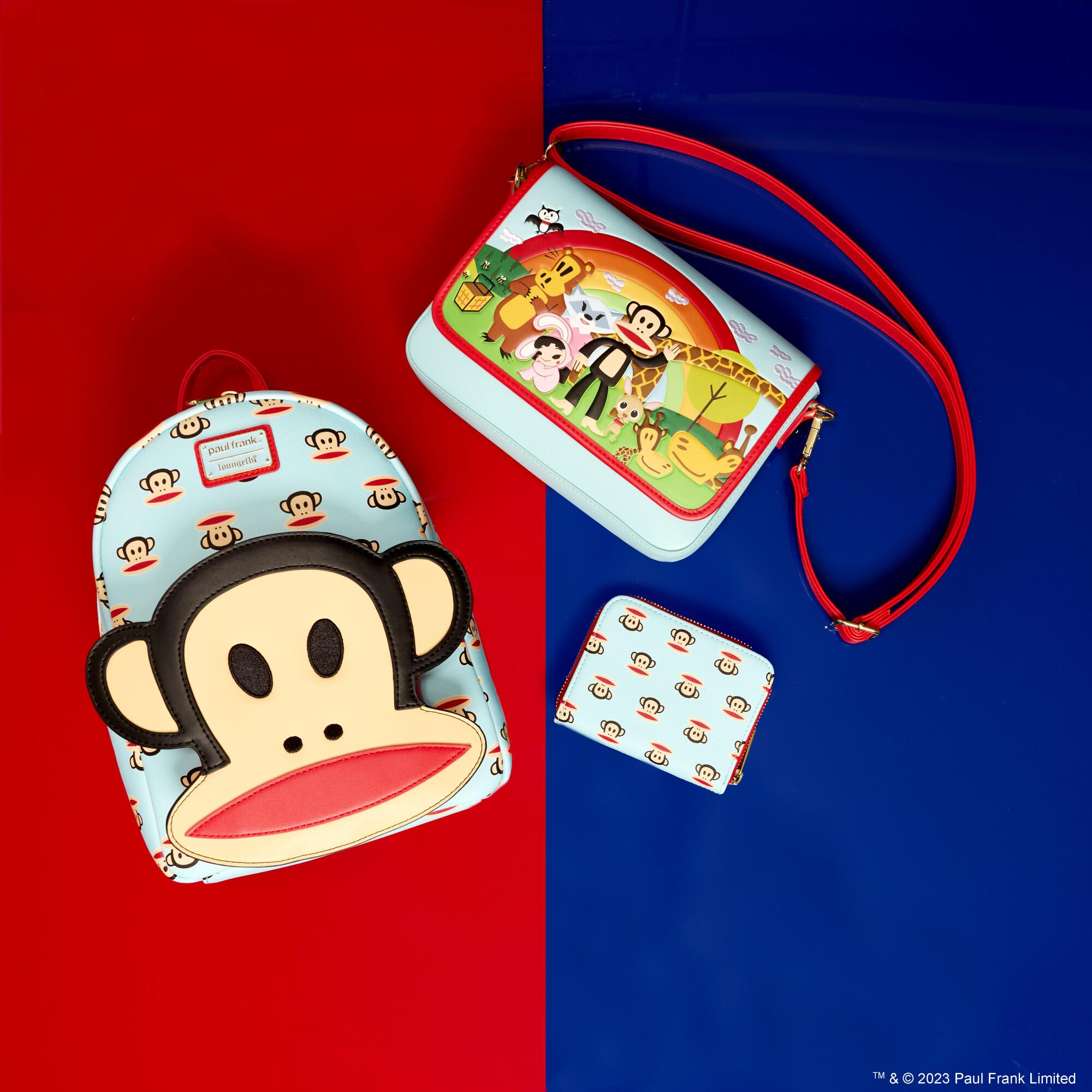 A Paul Frank monkey head on a backpack, wallet and smaller bag.