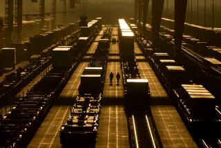 Workers walk among shipping containers at a BNSF intermodal terminal, Wednesday, Jan. 3, 2024, in Edgerton, Kan. On Friday, the U.S. government issues its December jobs report. (AP Photo/Charlie Riedel)