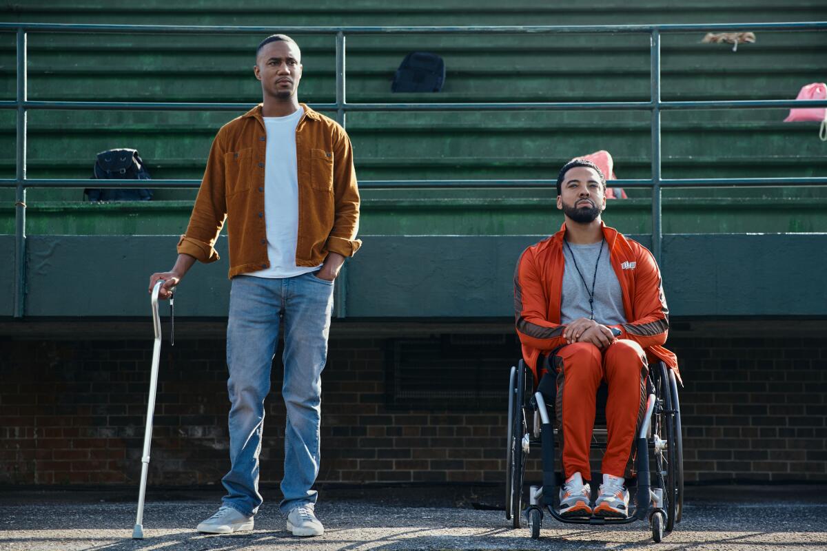 A man with a can stands alongside a man in a wheelchair
