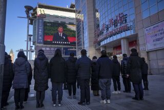 Gente mirando una emisión en vivo del funeral del expresidente de China Jiang Zemin, en la que el actual presidente de China, Xi Jinping, ofrece un discurso, en una pantalla en la calle comercial de Wangfujing en Beijing, el martes 6 de diciembre de 2022. (AP Foto/Andy Wong)