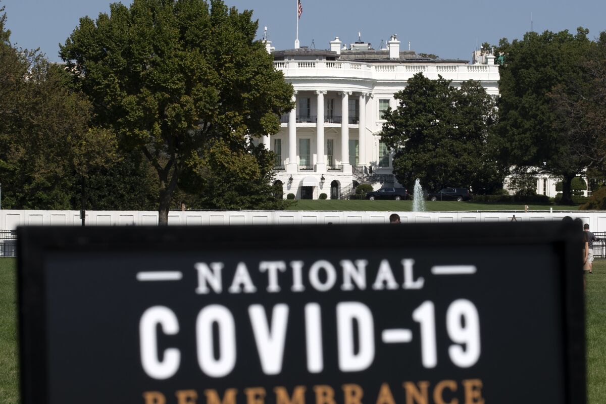 The White House is seen in the background as sign of the National COVID-19 Remembrance, event at The Ellipse outside of the White House, Sunday, Oct. 4, 2020, in Washington. More Americans blame the U.S. government than foreign powers for the coronavirus crisis in United States, rejecting the Trump administration’s contention that China is most at fault for the spread of the disease. That's according to a new poll by The University of Chicago Harris School of Public Policy and The Associated Press-NORC Center for Public Affairs Research.(AP Photo/Jose Luis Magana)