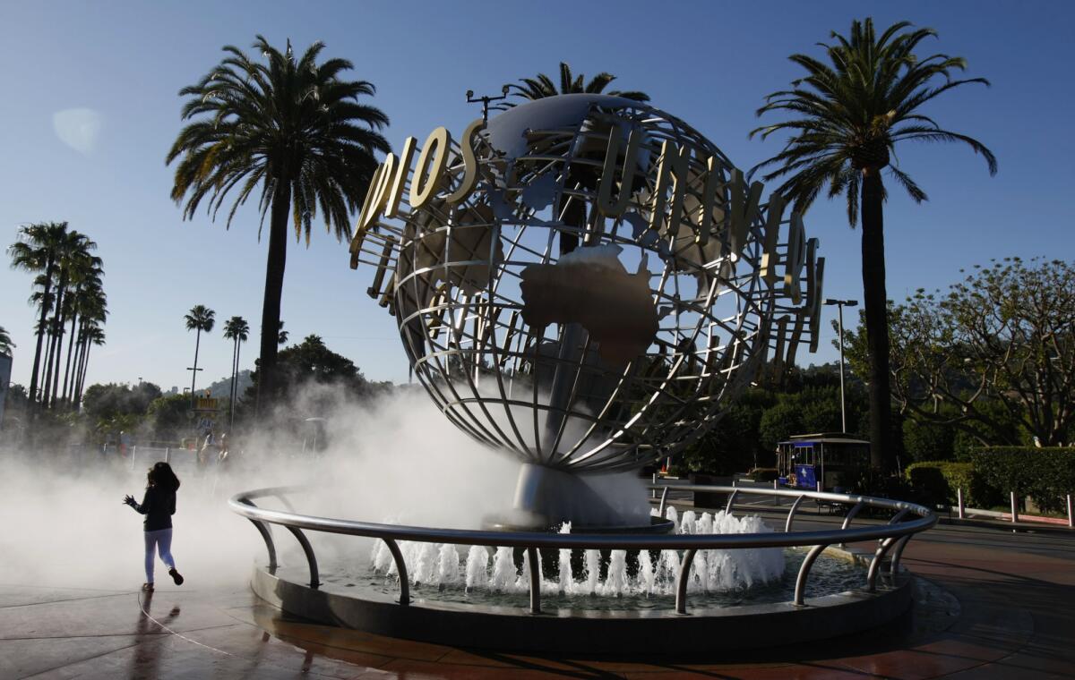 A girl runs through the spray at the entrance of Universal Studios Hollywood. Construction for a new Universal Studios park in Beijing will begin later this year.