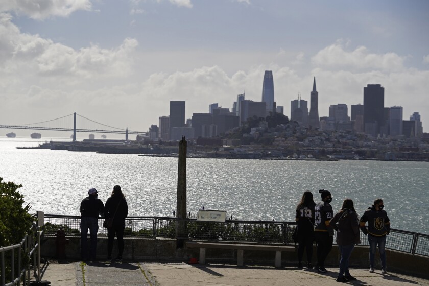 People look out at the views of the skyline and bay from Alcatraz Island in San Francisco, Monday, March 15, 2021. The historic island prison was reopened to visitors Monday after being closed since December because of the coronavirus threat. Visitors were also able to tour the inside of the main cell house for the first time in a year. (AP Photo/Eric Risberg)