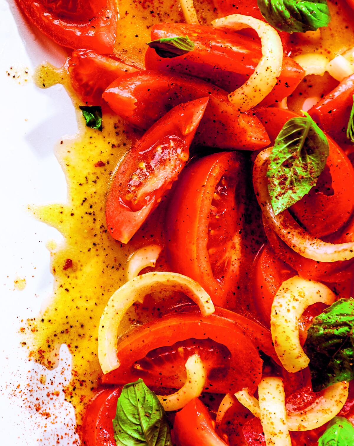 Wedges of tomatoes and hefty slices of onion with basil leaves in a vinaigrette.
