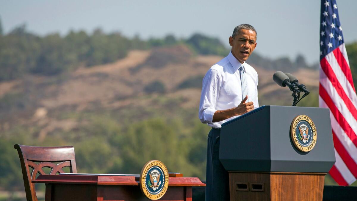 Then President Barack Obama speaks at Frank G. Bonelli Regional Park in San Dimas as he designates nearly 350,000 acres within the San Gabriel Mountains, background, a national monument on Oct. 10, 2014.