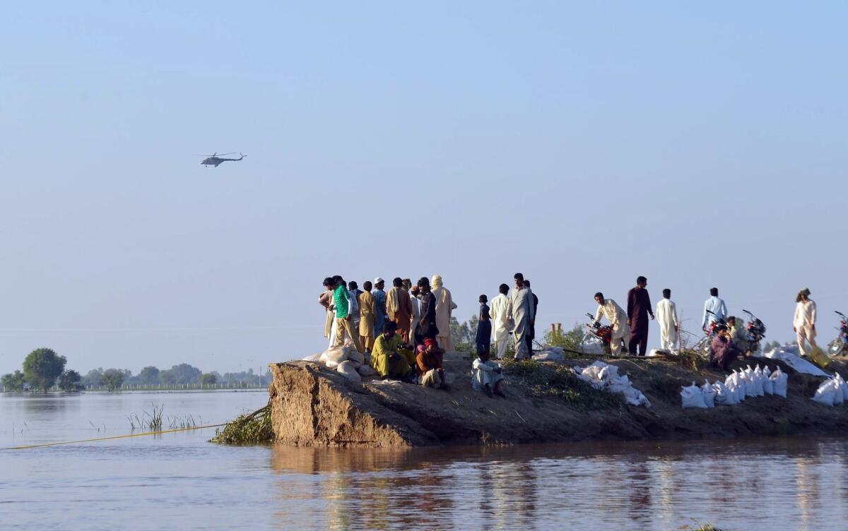 Pakistani villagers gather on higher ground as floodwaters enter in the Hafizabad district in Punjab province on Monday.