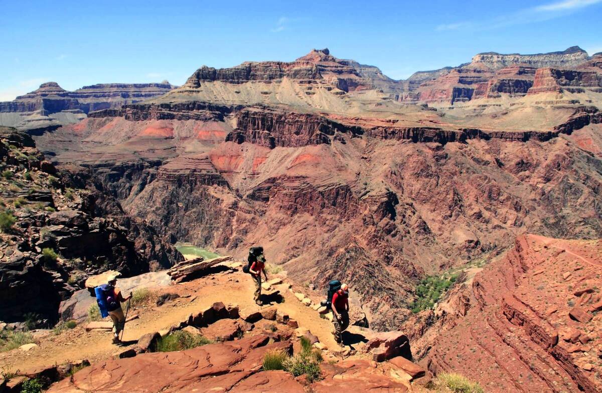 With the Grand Canyon as a magnificent backdrop, hikers make their way along the South Kaibab Trail. From here, there’s a glimpse of the Colorado River below.