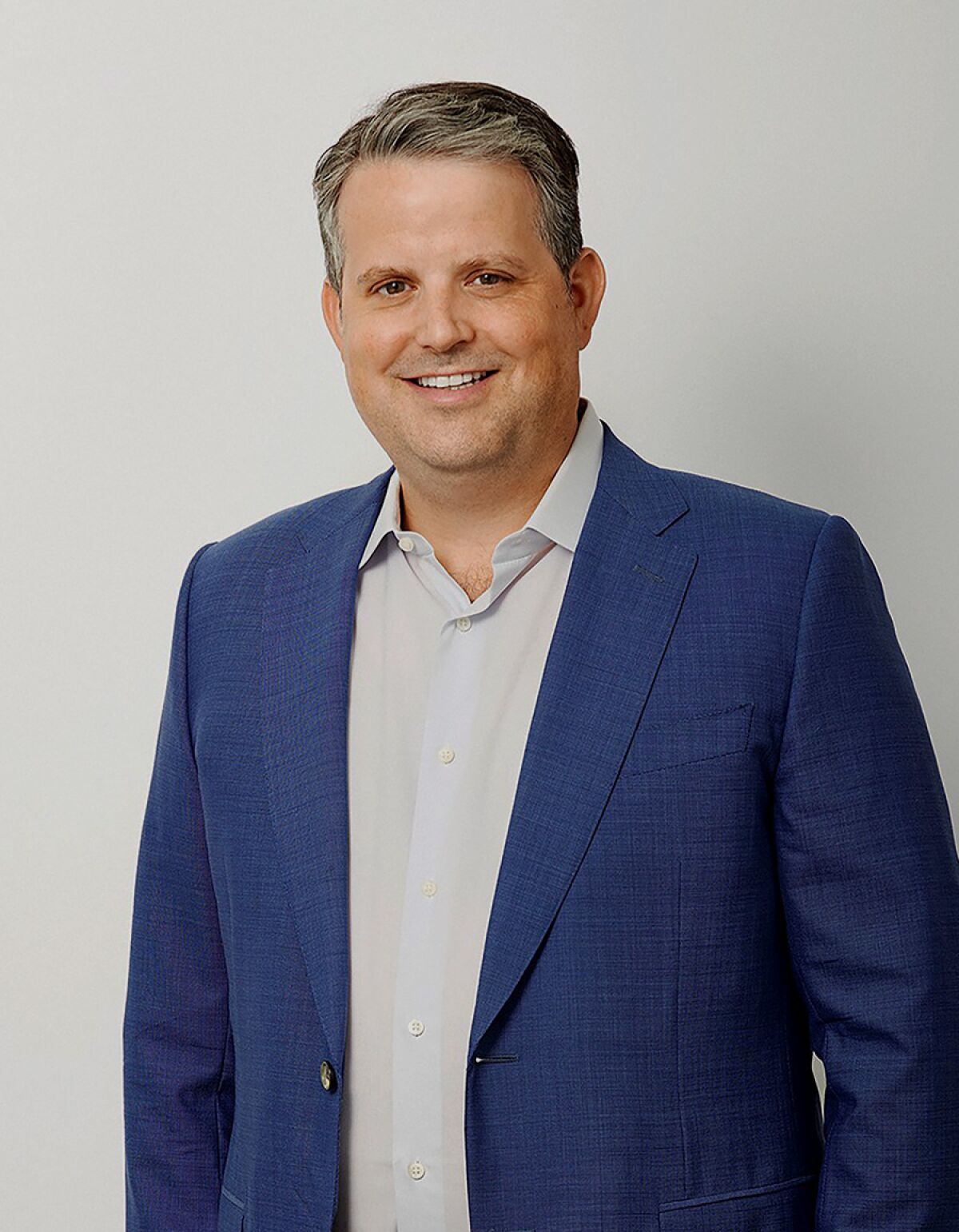 A man in a suit, smiling.