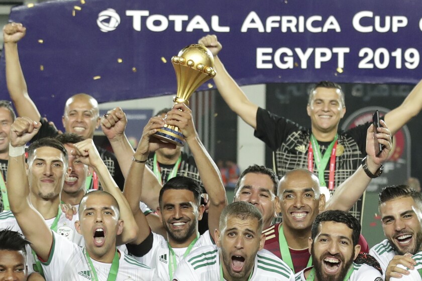 FILE - Algeria's captain Riyad Mahrez, center, holds up the trophy at the end of the African Cup of Nations final soccer match between Algeria and Senegal in Cairo International stadium in Cairo, Egypt, Friday, July 19, 2019. Algeria won 1-0. (AP Photo/Hassan Ammar, File)