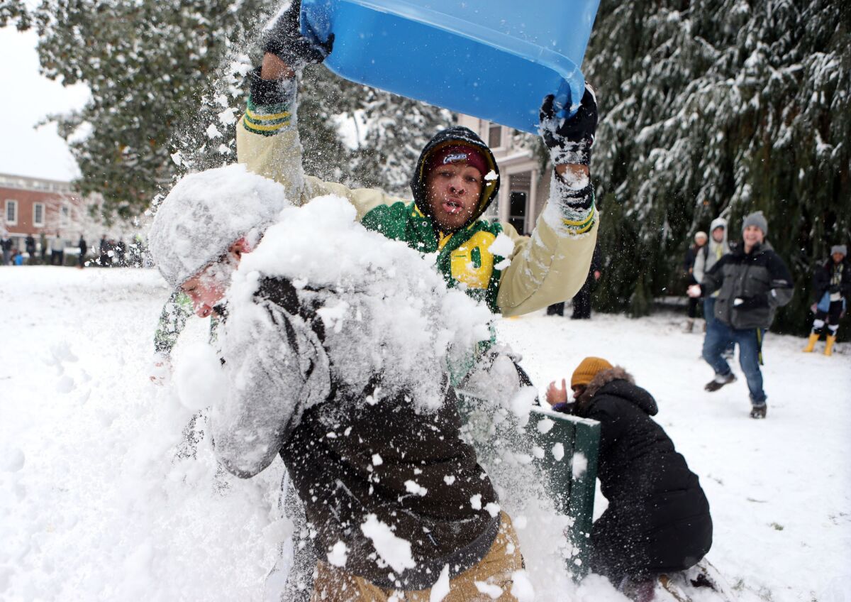 Pharaoh Brown dumps a tub load of snow on fellow student Charley Gibson during a snow battle involving students on campus Friday.
