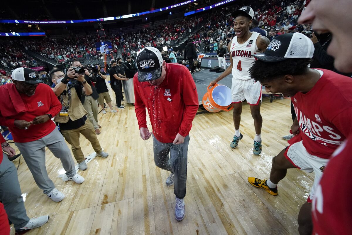Arizona head coach Tommy Lloyd is doused with water after by Arizona's Dalen Terry (4) after defeating UCLA in an NCAA college basketball game in the championship of the Pac-12 tournament Saturday, March 12, 2022, in Las Vegas. (AP Photo/John Locher)