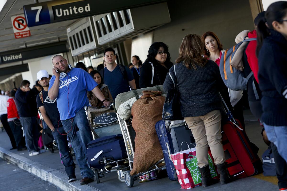 Travelers wait in line outside Terminal 7 at Los Angeles International Airport on Monday morning to reschedule their canceled flights. More than a dozen flights from LAX were canceled and many others were delayed because of winter storms in the Midwest and along the East Coast.