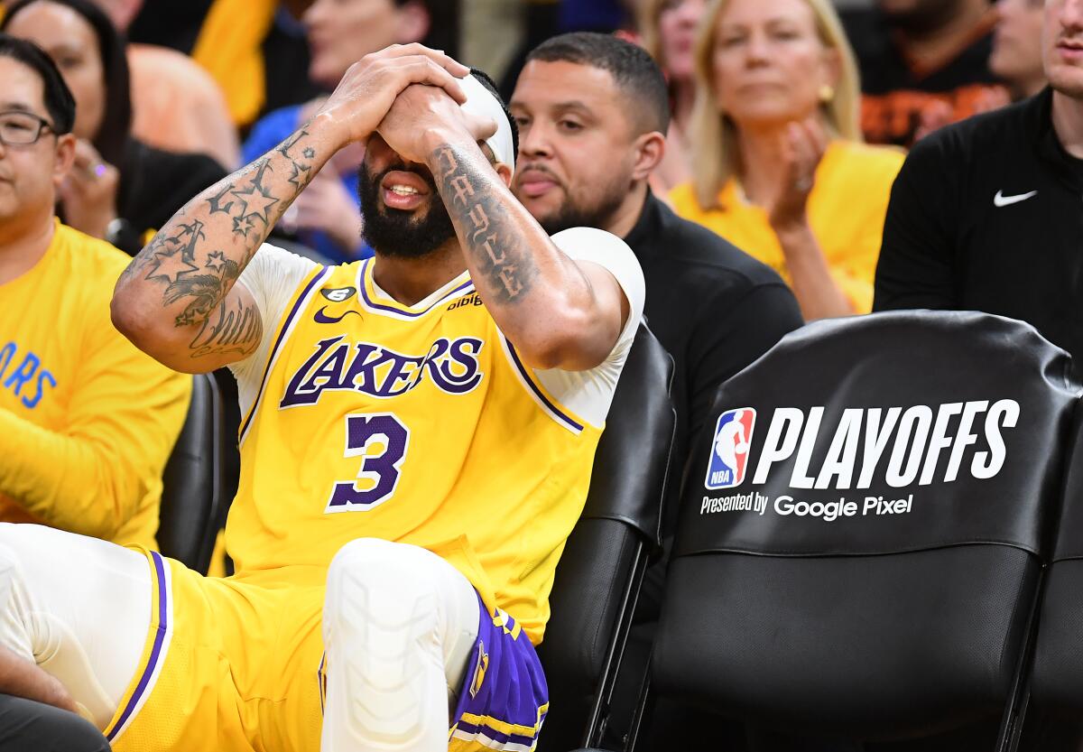 Lakers forward Anthony Davis holds his head with both hands as he sits on the bench after sustaining a head injury in Game 5.