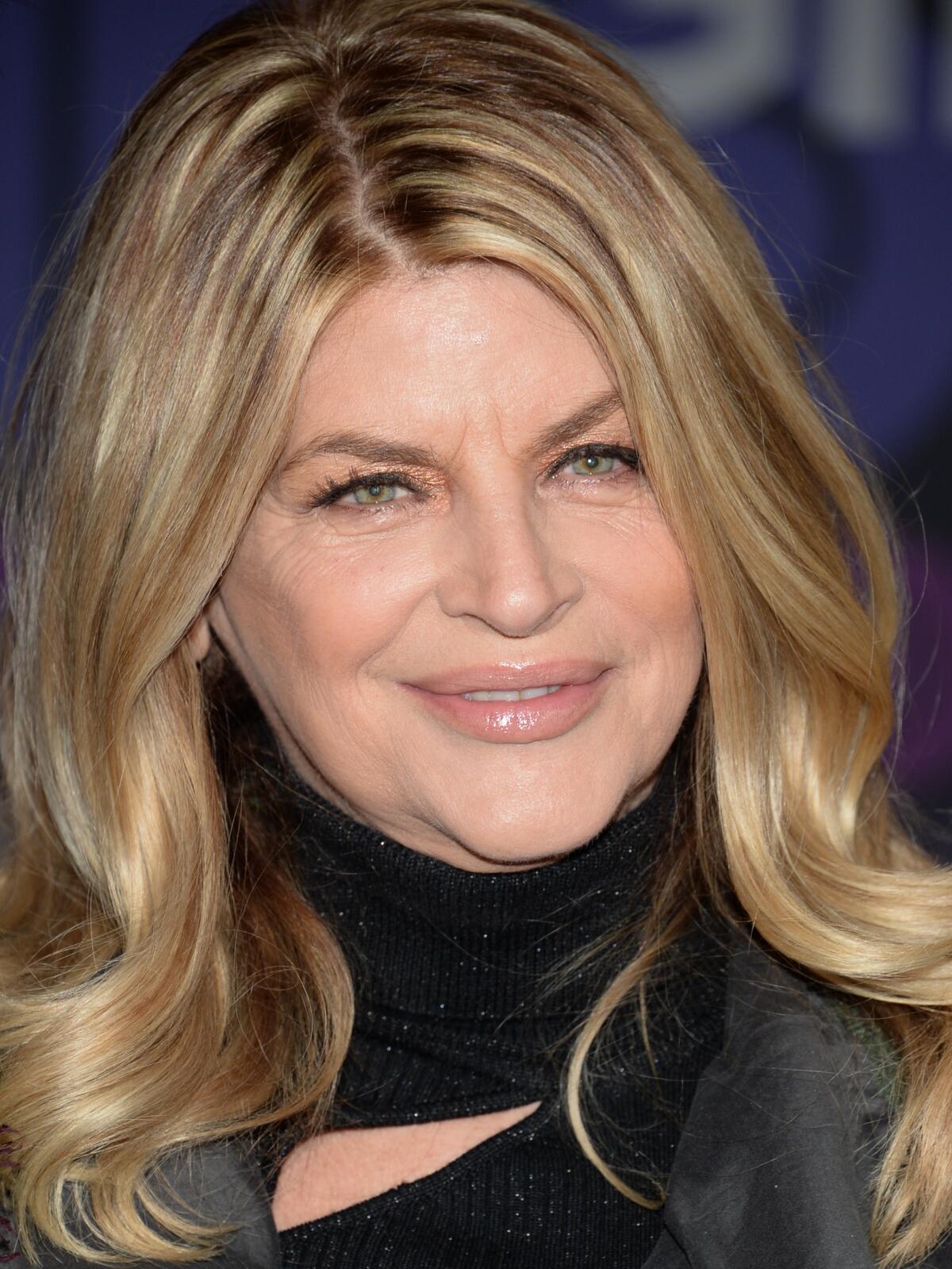 A woman with light brown hair wears a black shirt.