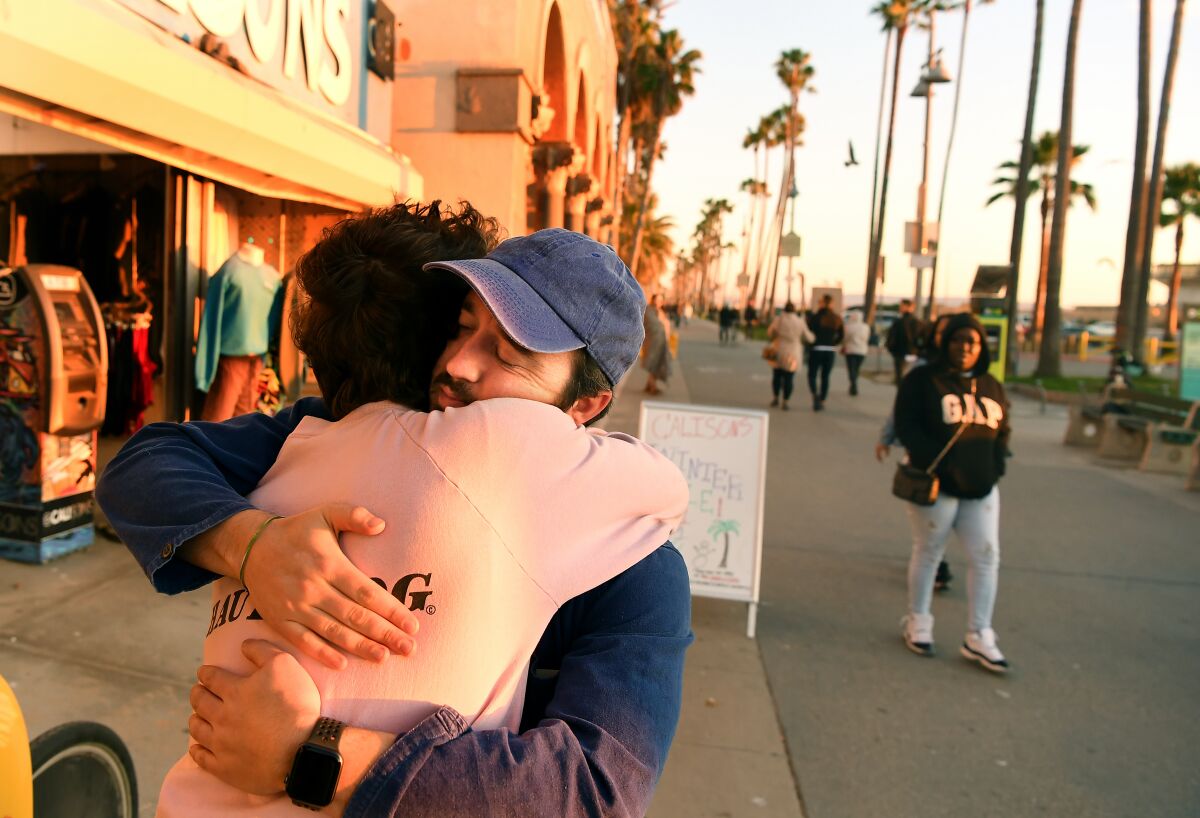 Jody Monkarsh's sons Henry, left, and Sam hug outside Jody Maroni's Sausage Kingdom on the Venice boardwalk during a final celebration after 40 years in business.