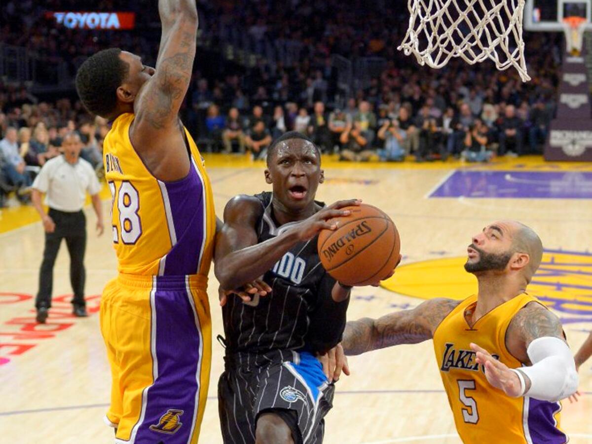 Magic guard Victor Oladipo splits Lakers forwards Tarik Black (28) and Carlos Boozer (5) as he goes up for a shot in the second half.