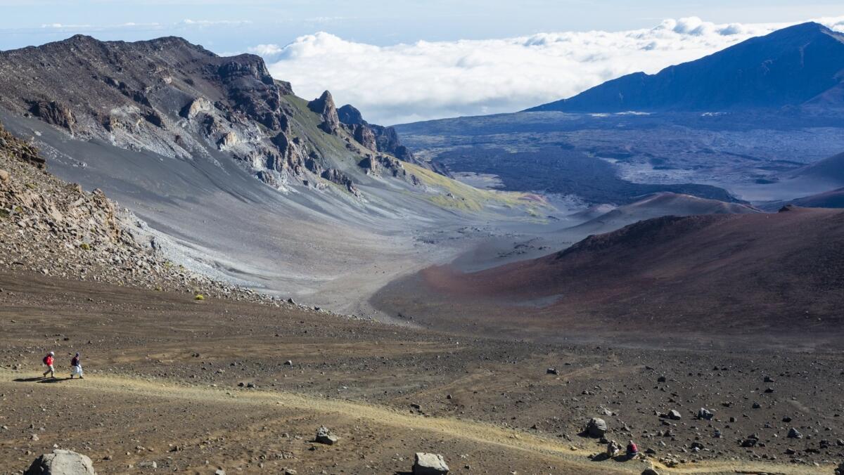 Hikers enjoy scenic vistas while walking a trail along the crater of Maui's Haleakala volcano.