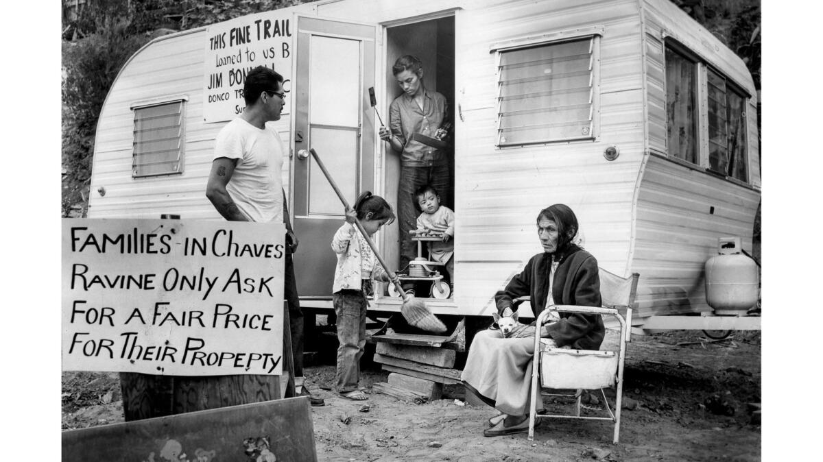 A family outside a trailer with a sign pleading for families in Chavez Ravine to be paid a fair price for their property