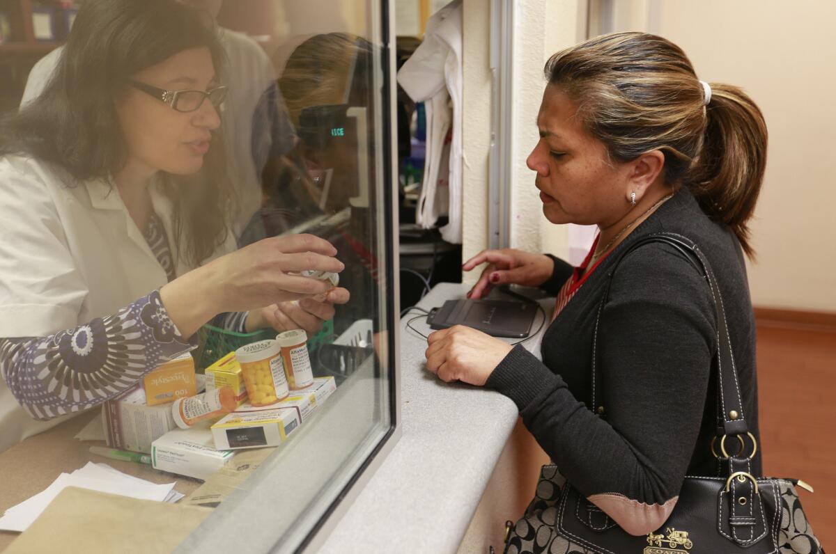 Patient Lucia Jimenez has her prescription filled by pharmacist Alaria Kiraz, left, at AltaMed clinic in East Los Angeles. AltaMed clinics serve patients who are part of L.A. Care Health Plan.