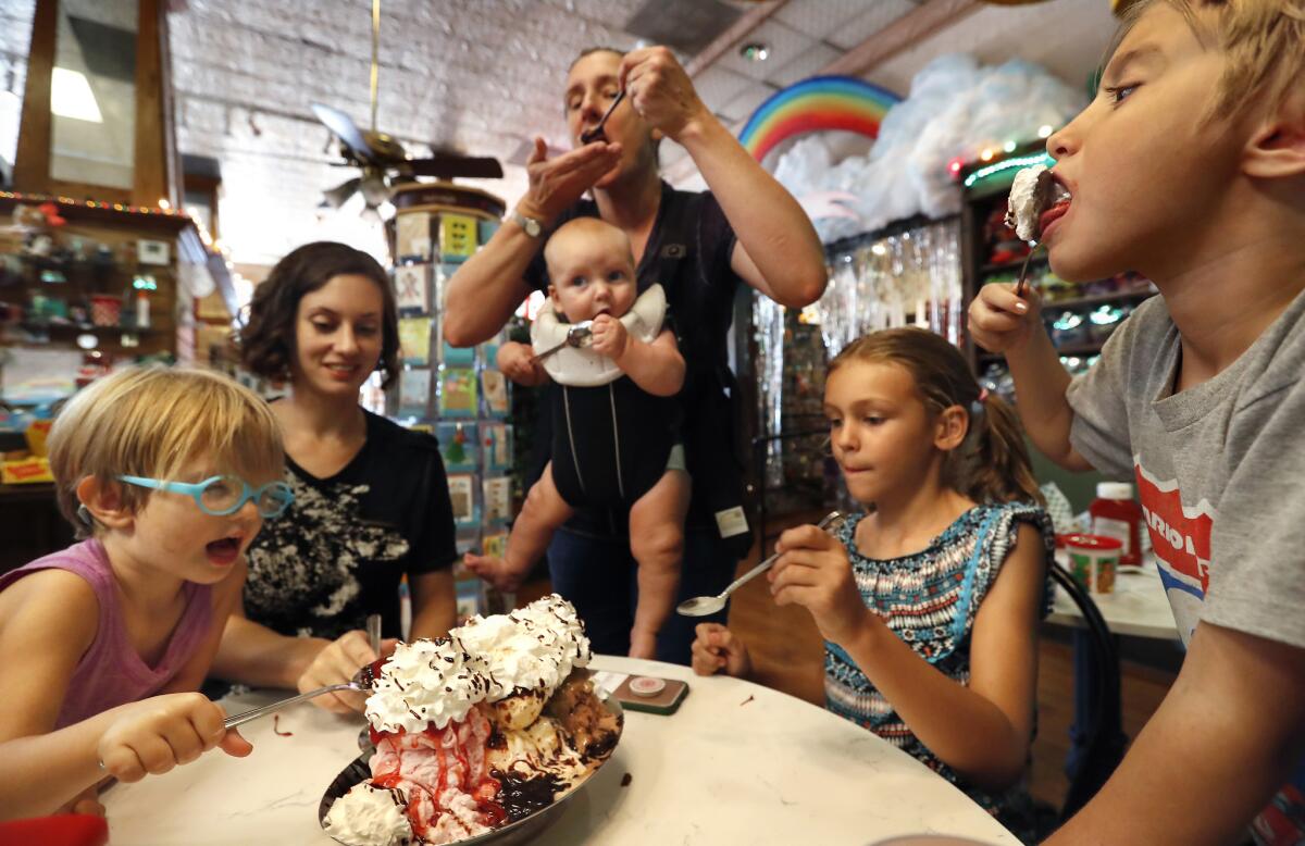 Left to right: Robyn Heinze, her mother Jacqueline, Emily Beaghan, her baby boy Winston and daughters Georgia and Piper dig into a banana split at Fair Oaks Pharmacy, an old-school pharmacy and soda fountain in South Pasadena.