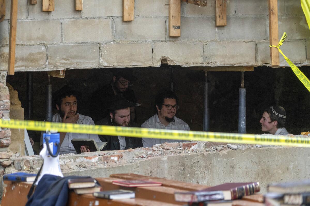 Estudiantes judíos jasídicos están sentados detrás de una brecha en la pared de una sinagoga