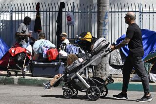 Jarvis Leverson pushes his children Jordan, 1 1/2, and Jetson, 3, past a homeless encampment in downtown San Diego Mar. 9, 2023 in San Diego. The encampment is four blocks from his home. (Photo by Denis Poroy)