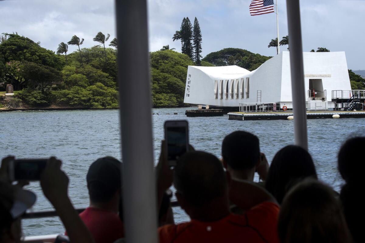 Visitors photograph the USS Arizona Memorial at the World War II Valor in the Pacific National Monument in Honolulu.
